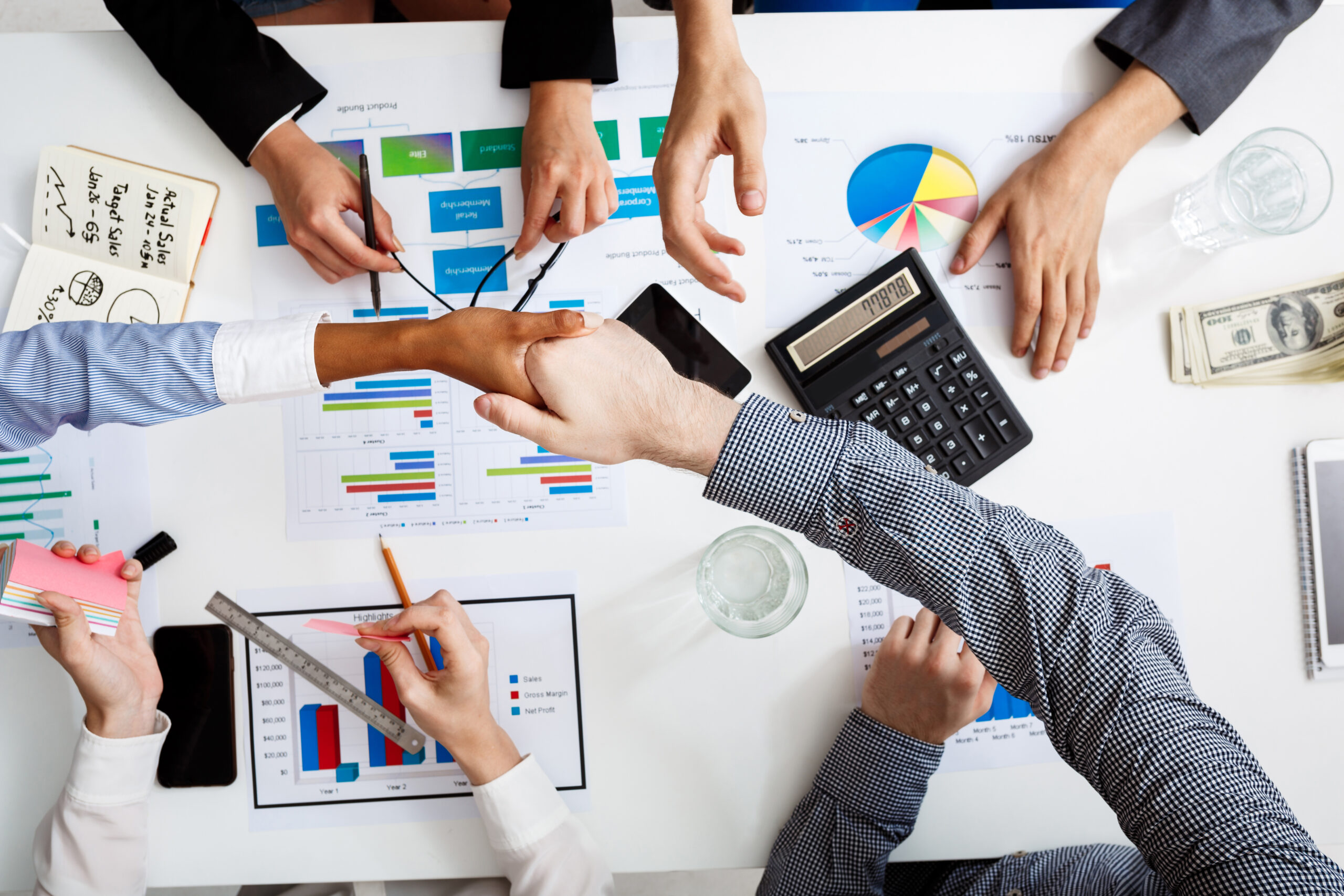 Picture of businessmen's hands on white table with documents, coffee and drafts